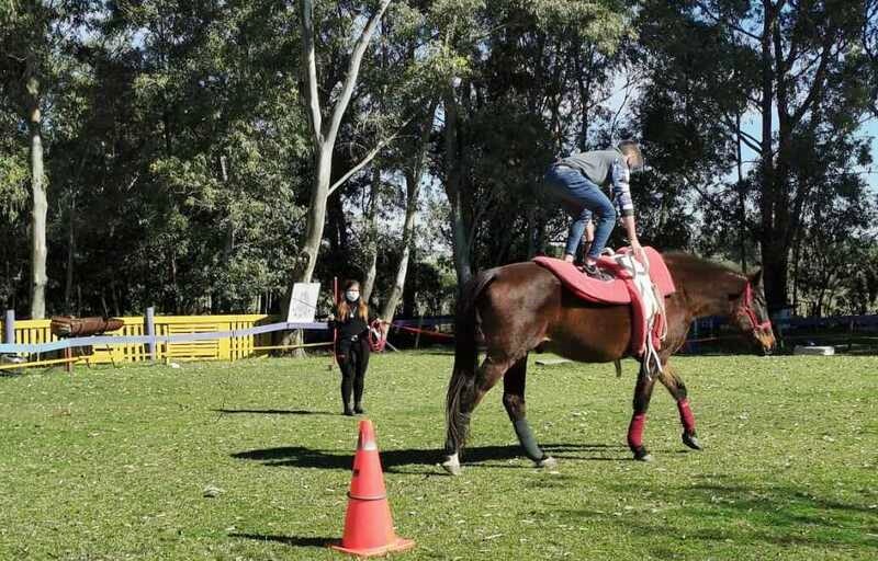Joven haciendo equilibrio sobre el caballo