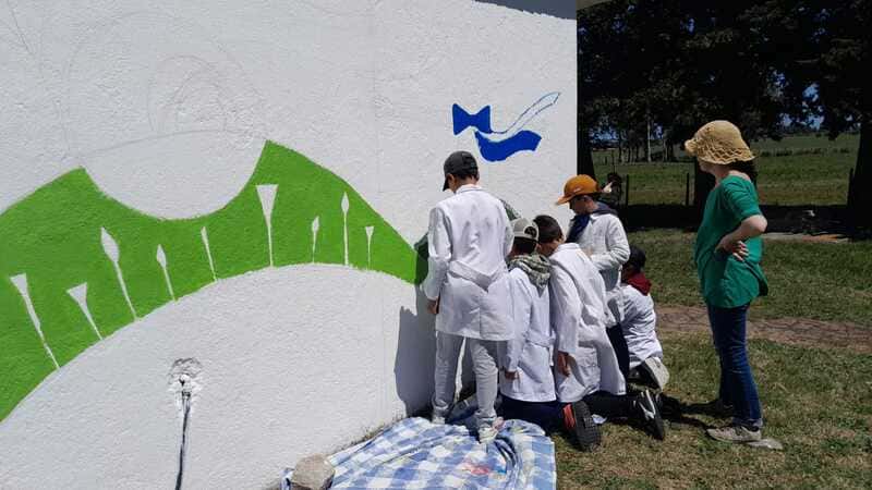 Niños de la escuela comienzan a pintar un mural en la pared